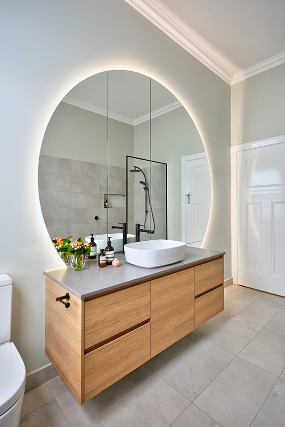 This is an example of a large contemporary 3/4 bathroom in Melbourne with flat-panel cabinets, brown cabinets, a freestanding tub, an open shower, a wall-mount toilet, porcelain tile, porcelain floors, a vessel sink and solid surface benchtops.