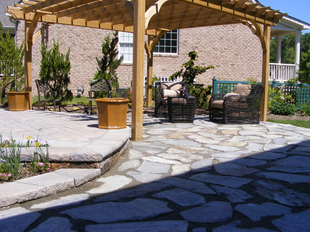 This is an example of a large transitional backyard patio in Other with natural stone pavers.