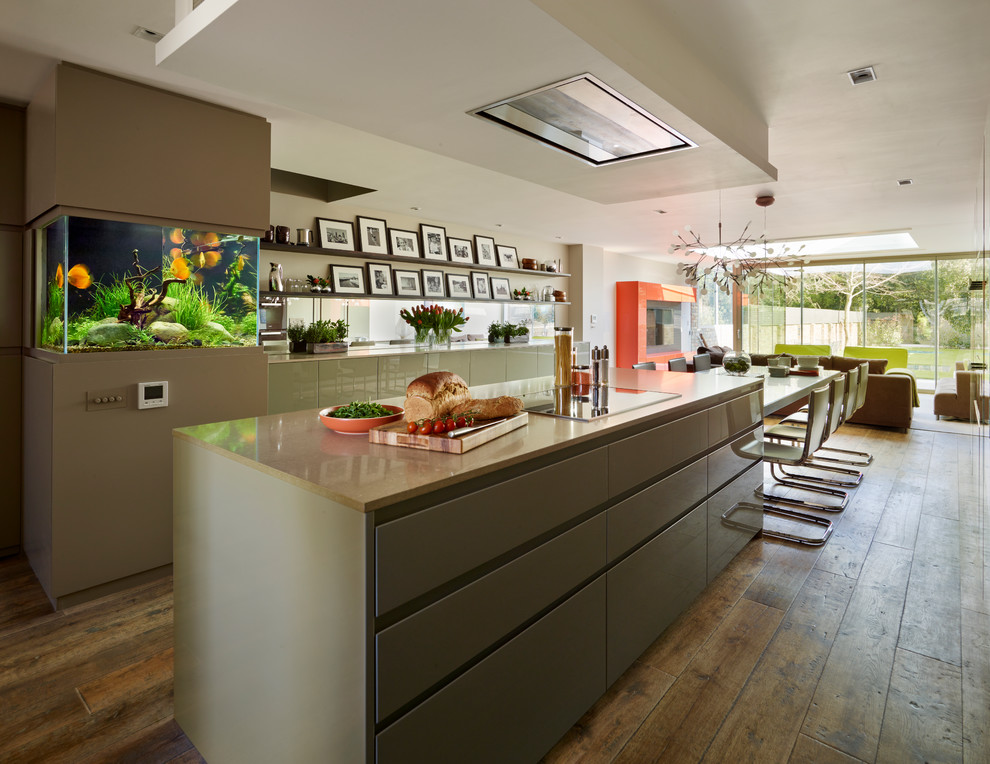 Design ideas for a contemporary open plan kitchen in London with flat-panel cabinets, solid surface benchtops, mirror splashback, medium hardwood floors and with island.