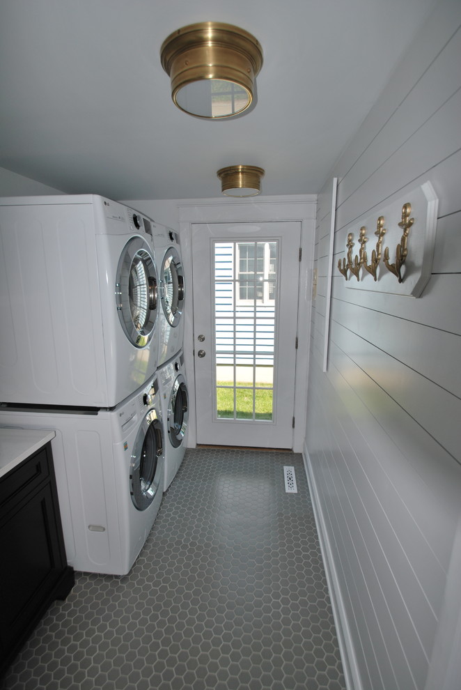 This is an example of a mid-sized beach style galley utility room in DC Metro with an undermount sink, beaded inset cabinets, blue cabinets, quartz benchtops, white walls, ceramic floors, a stacked washer and dryer, grey floor and white benchtop.