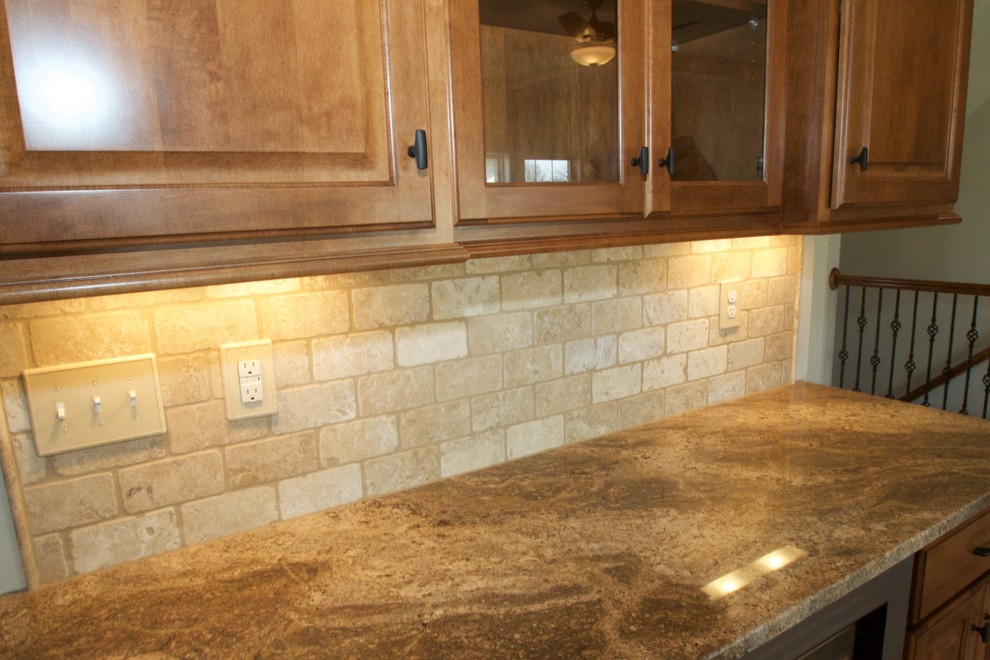 Large transitional galley medium tone wood floor open concept kitchen photo in Milwaukee with an undermount sink, raised-panel cabinets, medium tone wood cabinets, granite countertops, beige backsplash, stone tile backsplash, stainless steel appliances and an island