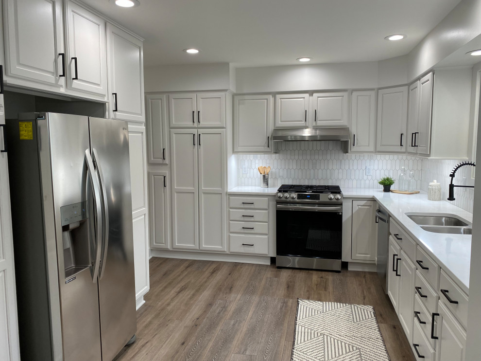 Mid-sized elegant l-shaped brown floor kitchen photo in Columbus with an undermount sink, raised-panel cabinets, white cabinets, quartz countertops, white backsplash, marble backsplash, stainless steel appliances and white countertops