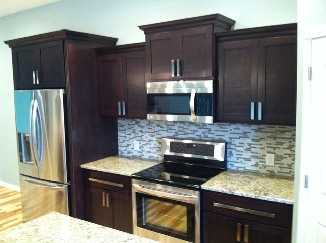 Enclosed kitchen - large galley light wood floor enclosed kitchen idea in Cedar Rapids with a drop-in sink, flat-panel cabinets, black cabinets, metallic backsplash and an island