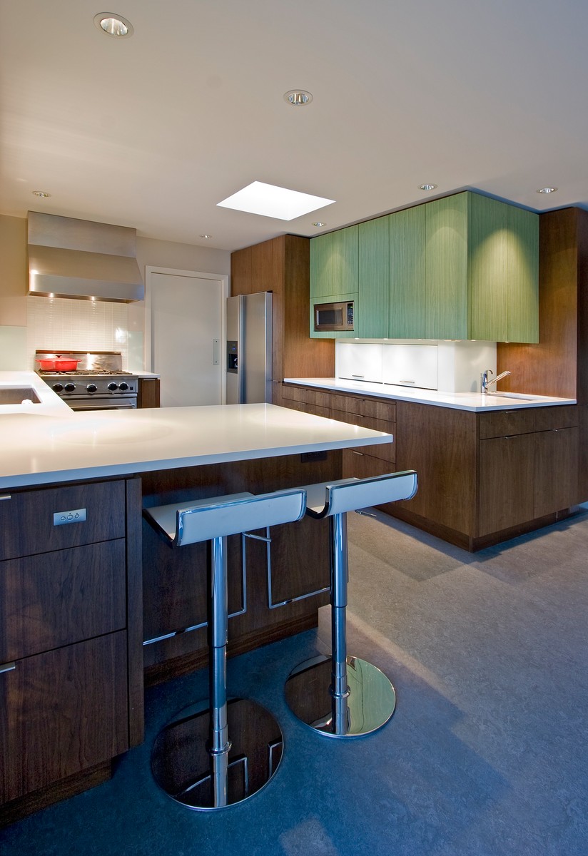 Midcentury l-shaped kitchen with an undermount sink, flat-panel cabinets, dark wood cabinets, white splashback, ceramic splashback, stainless steel appliances, concrete floors, with island and grey floor.