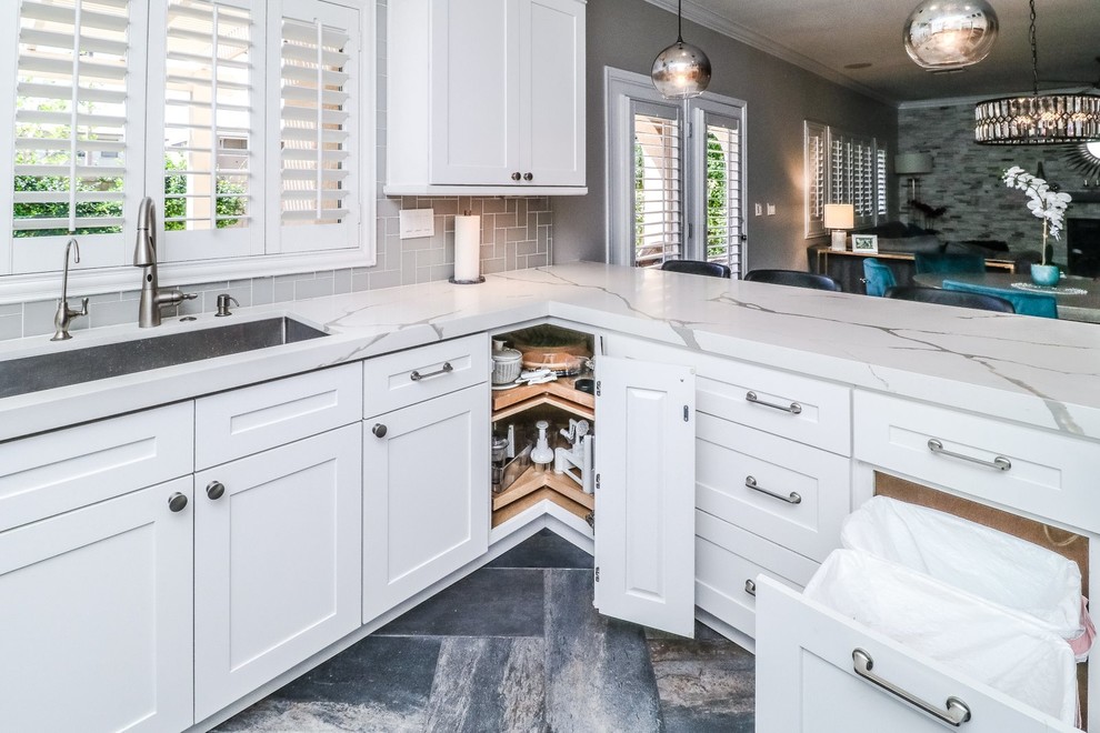 Inspiration for a mid-sized transitional u-shaped separate kitchen in Las Vegas with an undermount sink, shaker cabinets, white cabinets, quartzite benchtops, grey splashback, porcelain splashback, stainless steel appliances, porcelain floors, a peninsula, grey floor and white benchtop.