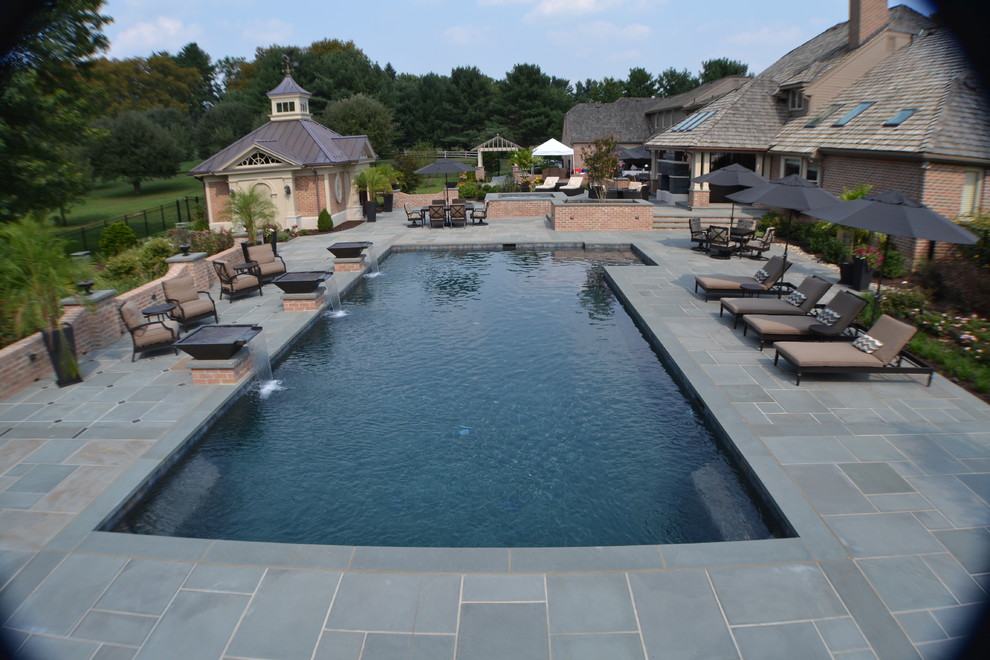 Large traditional backyard rectangular lap pool in Philadelphia with a water feature and natural stone pavers.