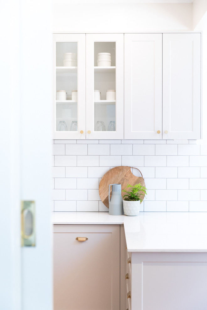 Mid-sized transitional l-shaped eat-in kitchen in Melbourne with a farmhouse sink, shaker cabinets, grey cabinets, quartz benchtops, white splashback, subway tile splashback, stainless steel appliances, medium hardwood floors and with island.