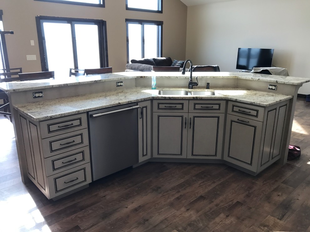 Example of a large classic u-shaped dark wood floor and brown floor open concept kitchen design with flat-panel cabinets, distressed cabinets, granite countertops, a double-bowl sink, stainless steel appliances and an island
