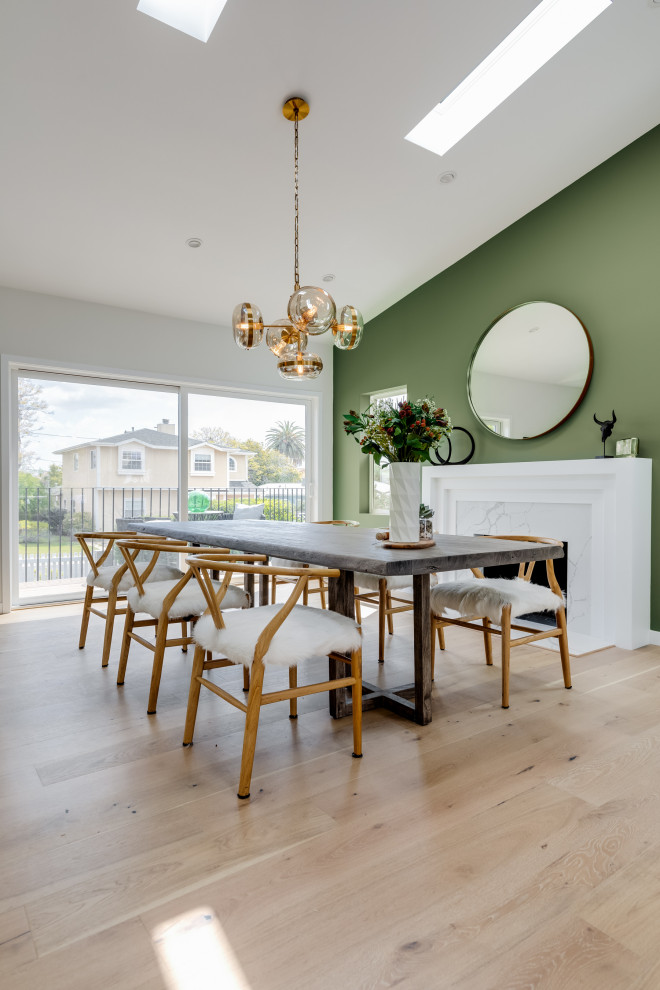Cette photo montre une grande salle à manger ouverte sur la cuisine chic avec un mur vert, parquet clair, une cheminée standard, un manteau de cheminée en bois et un plafond voûté.