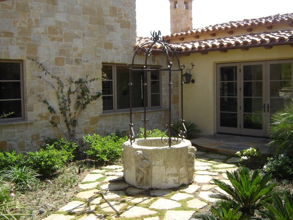 Photo of a mid-sized mediterranean one-storey beige exterior in Orange County with stone veneer.
