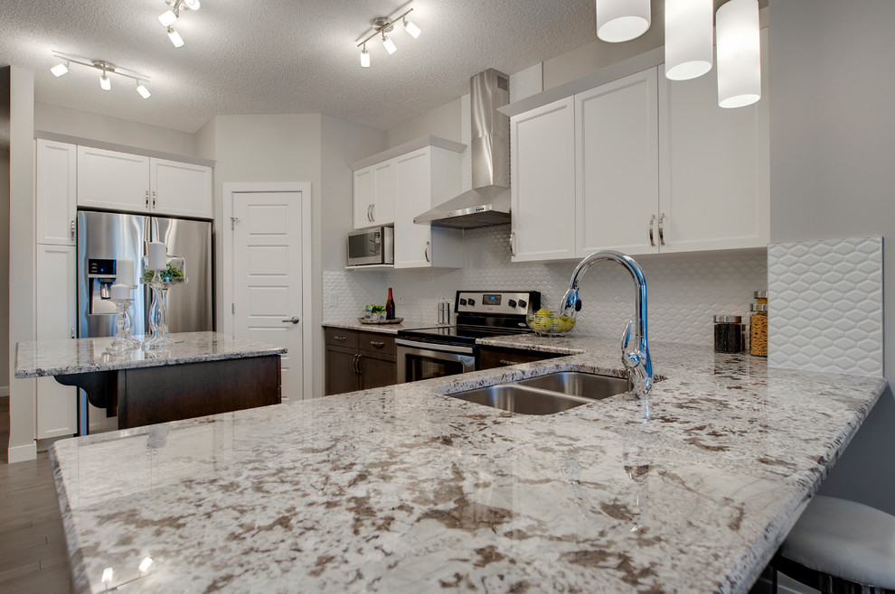 Inspiration for a mid-sized transitional u-shaped medium tone wood floor eat-in kitchen remodel in Edmonton with an undermount sink, shaker cabinets, yellow cabinets, granite countertops, white backsplash, ceramic backsplash, stainless steel appliances and an island