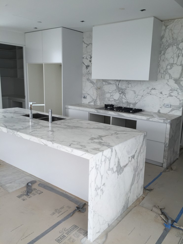 Photo of an expansive modern eat-in kitchen in Melbourne with marble benchtops, white splashback, stone slab splashback and with island.