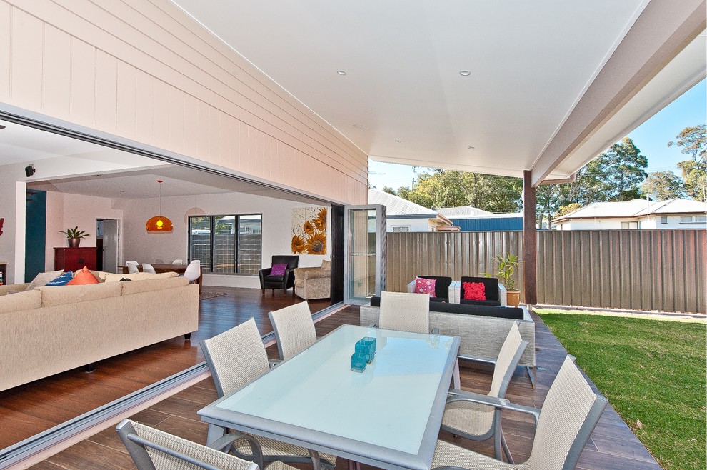 This is an example of a mid-sized contemporary backyard deck in Brisbane with a roof extension.