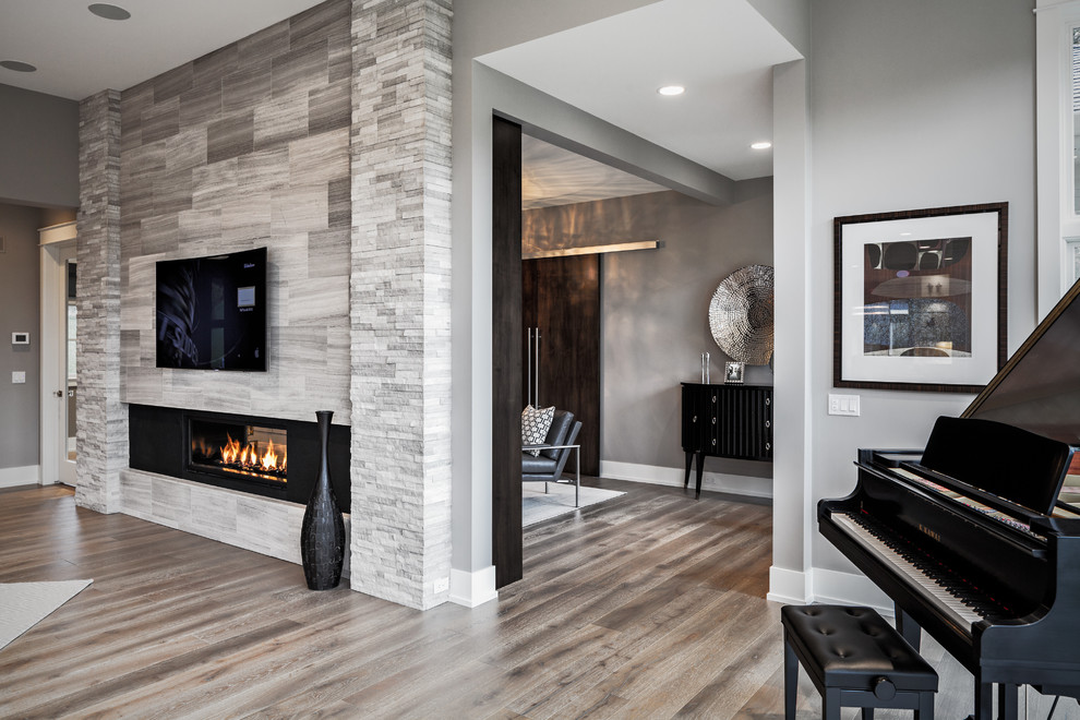 Large transitional master bedroom in Grand Rapids with grey walls, light hardwood floors, a two-sided fireplace and a stone fireplace surround.