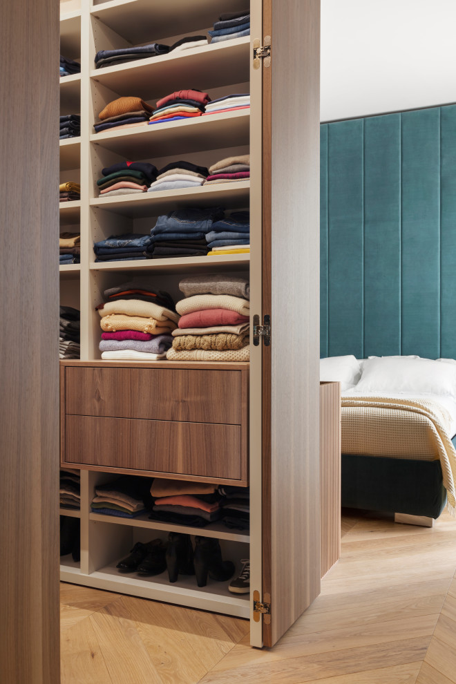 Foto de armario vestidor unisex minimalista de tamaño medio con armarios con paneles lisos, puertas de armario de madera oscura y suelo de madera en tonos medios