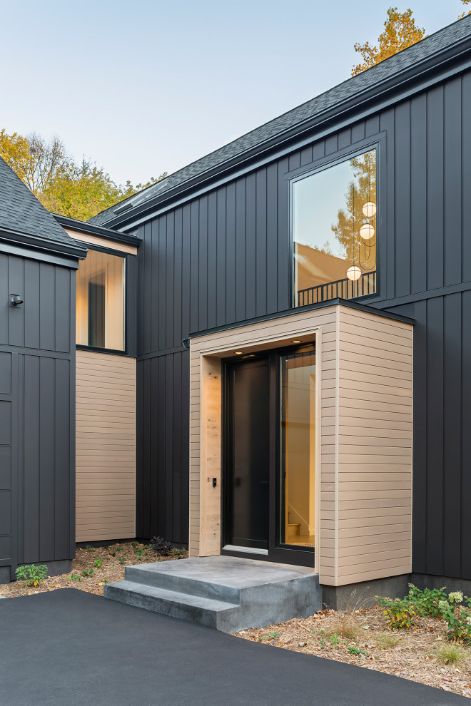 This is an example of a large scandinavian two-storey black house exterior in Minneapolis with wood siding, a gable roof, a shingle roof, a black roof and board and batten siding.