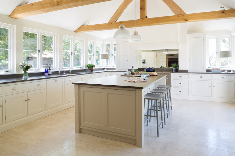 Inspiration for a large transitional l-shaped open plan kitchen in Essex with metallic splashback, mirror splashback, stainless steel appliances, limestone floors, with island, recessed-panel cabinets, an undermount sink and white cabinets.