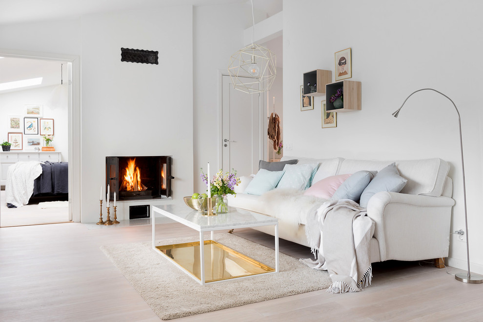 Mid-sized scandinavian open concept living room in Gothenburg with white walls, light hardwood floors, a standard fireplace and a plaster fireplace surround.