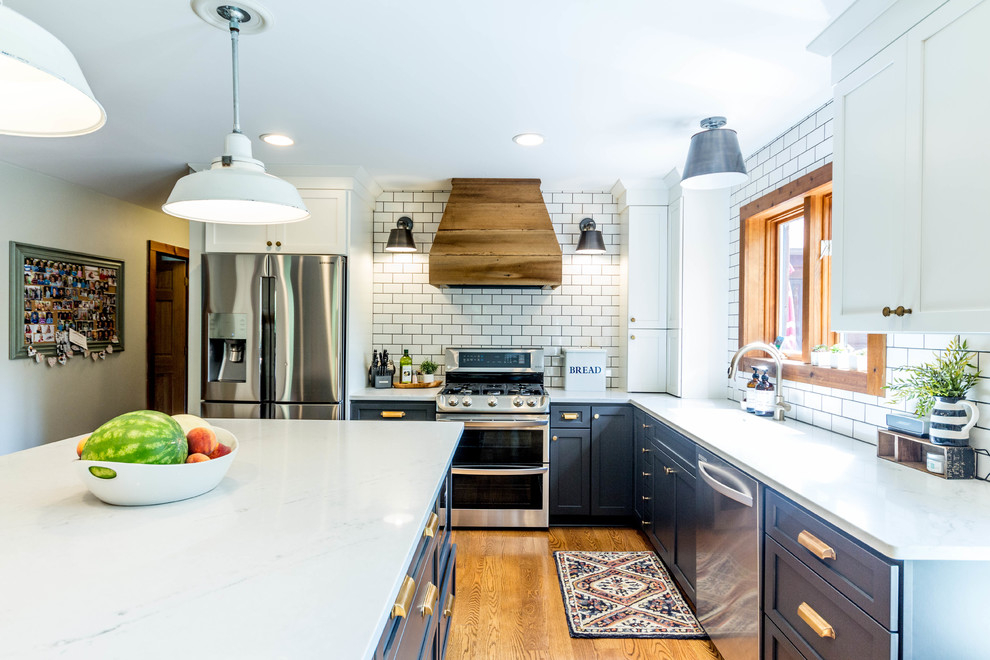 Photo of a mid-sized country l-shaped eat-in kitchen in Detroit with an undermount sink, flat-panel cabinets, grey cabinets, quartz benchtops, yellow splashback, subway tile splashback, stainless steel appliances, medium hardwood floors, with island and brown floor.