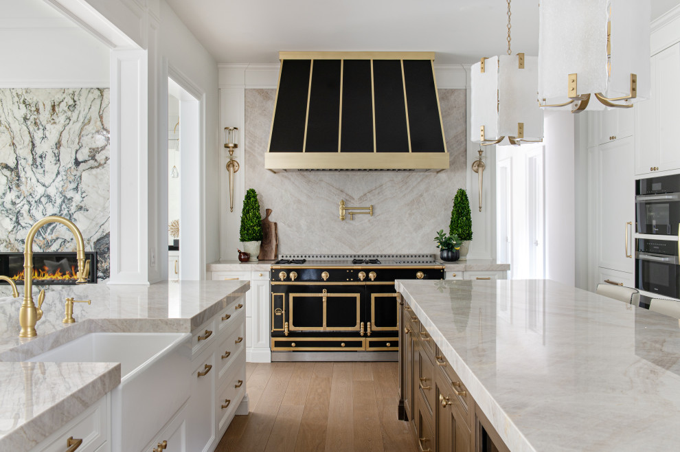 Example of a large transitional u-shaped light wood floor open concept kitchen design in Toronto with a farmhouse sink, beaded inset cabinets, white cabinets, multicolored backsplash, black appliances, an island and multicolored countertops