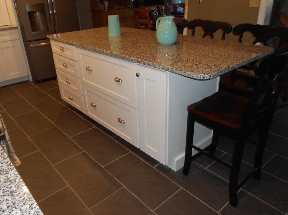 This is an example of a mid-sized transitional l-shaped eat-in kitchen in Portland Maine with an undermount sink, shaker cabinets, white cabinets, granite benchtops, white splashback, subway tile splashback, stainless steel appliances, slate floors and with island.