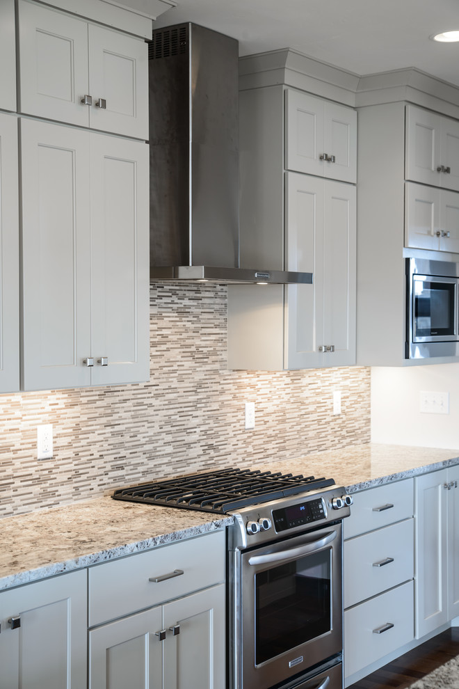 Transitional l-shaped medium tone wood floor open concept kitchen photo with a farmhouse sink, shaker cabinets, white cabinets, stainless steel appliances and an island