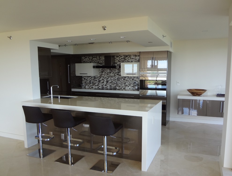 Mid-sized modern galley eat-in kitchen in Miami with an undermount sink, flat-panel cabinets, white cabinets, solid surface benchtops, multi-coloured splashback, matchstick tile splashback, stainless steel appliances, marble floors, a peninsula and beige floor.