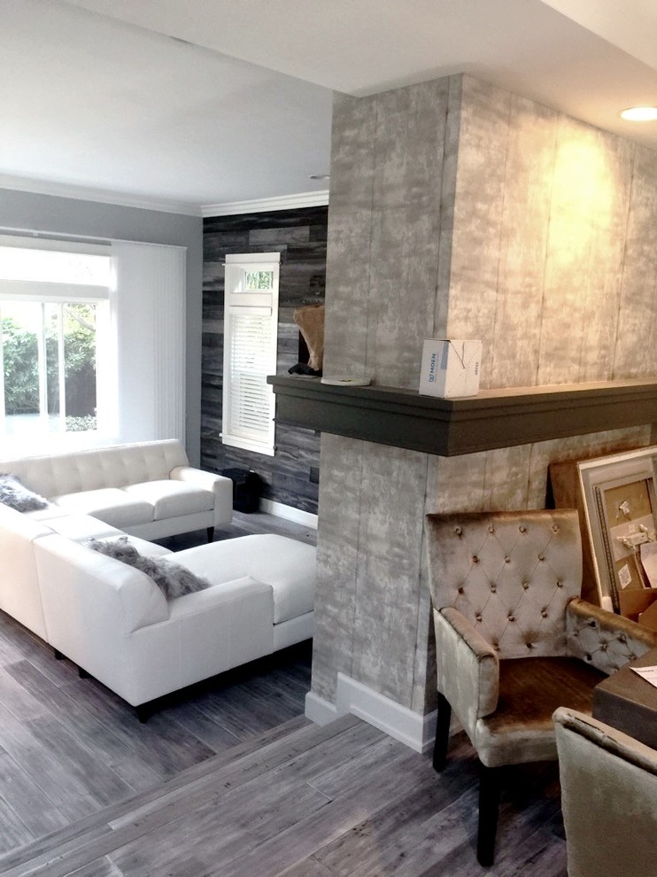 Inspiration for a large country open concept living room in San Diego with grey walls, light hardwood floors, a standard fireplace, a concrete fireplace surround and a wall-mounted tv.