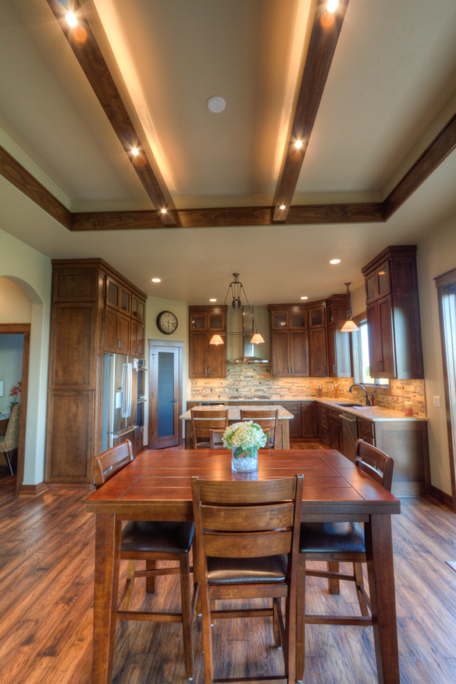 This is an example of an arts and crafts u-shaped eat-in kitchen in Milwaukee with an undermount sink, shaker cabinets, dark wood cabinets, granite benchtops, multi-coloured splashback, stainless steel appliances, medium hardwood floors and with island.