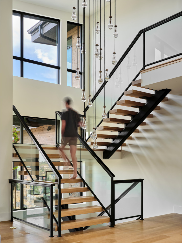 Modelo de escalera en U contemporánea extra grande con escalones de madera, contrahuellas de madera y barandilla de vidrio