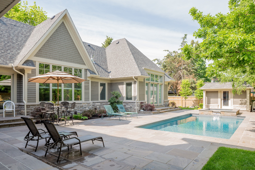 This is an example of a large traditional backyard rectangular pool in Toronto with a hot tub.