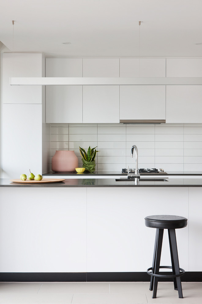 Kitchen in Melbourne with a drop-in sink, white cabinets, white splashback, ceramic splashback, stainless steel appliances and with island.