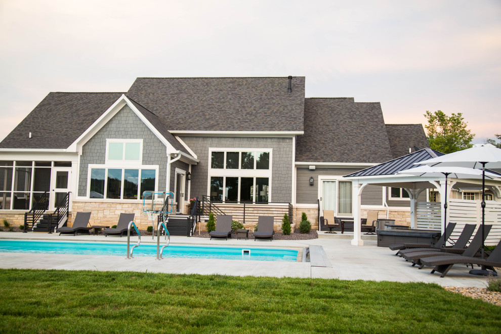 Large arts and crafts backyard rectangular pool in Indianapolis with a hot tub and concrete slab.