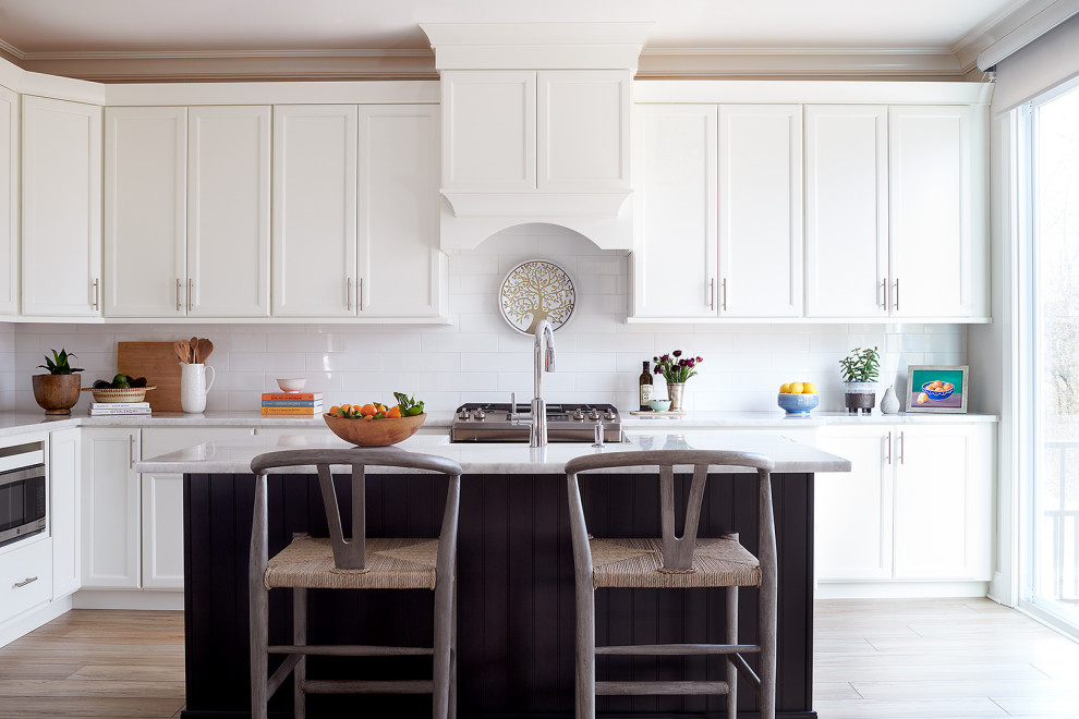 Inspiration for a mid-sized transitional l-shaped open plan kitchen in Philadelphia with a farmhouse sink, shaker cabinets, white cabinets, quartzite benchtops, white splashback, ceramic splashback, stainless steel appliances, vinyl floors, with island, brown floor and white benchtop.