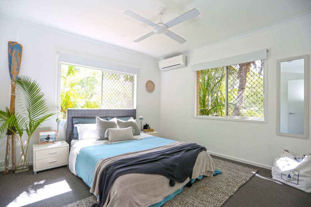 This is an example of a beach style guest bedroom in Other with white walls, carpet and grey floor.