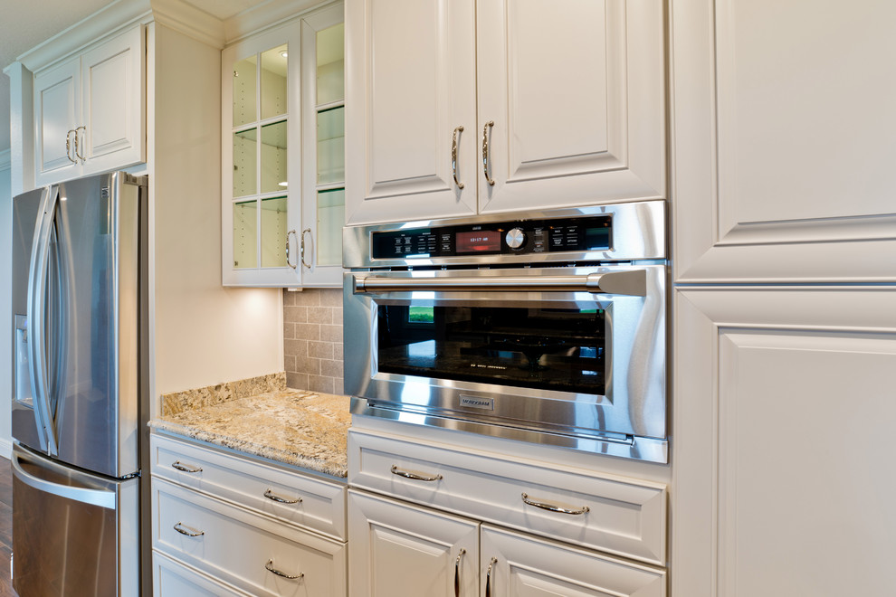 Example of a large transitional galley porcelain tile eat-in kitchen design in Miami with an undermount sink, raised-panel cabinets, white cabinets, granite countertops, gray backsplash, porcelain backsplash, stainless steel appliances and an island