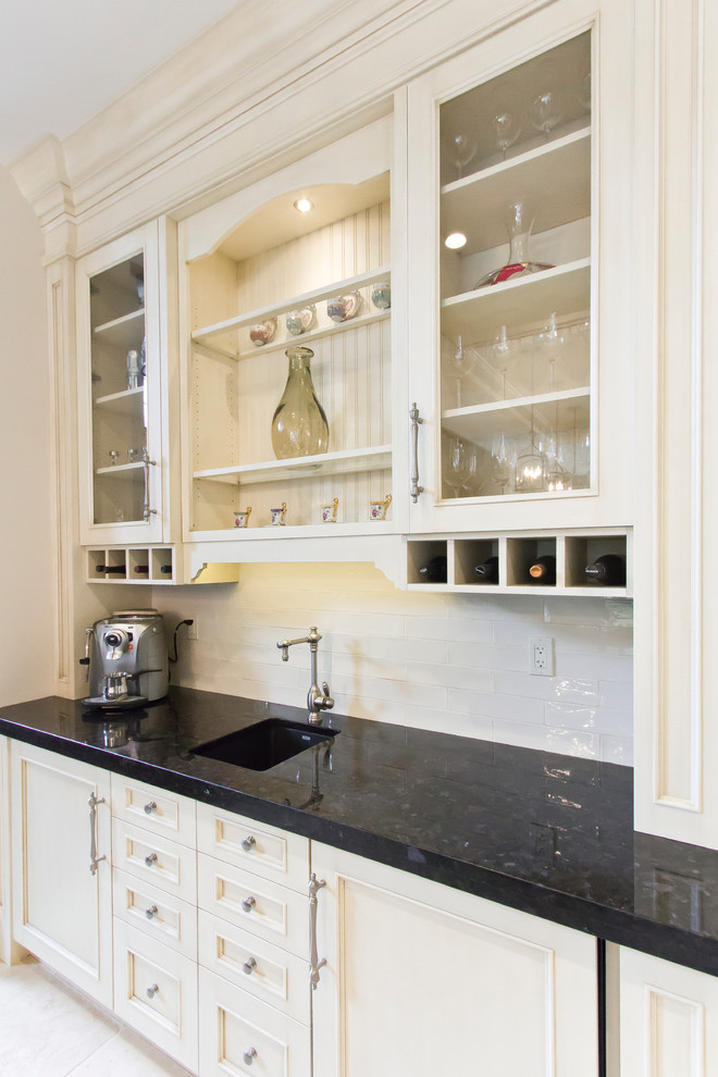 This is an example of a large traditional galley seated home bar in Toronto with a drop-in sink, raised-panel cabinets, white cabinets, tile benchtops, white splashback, subway tile splashback and ceramic floors.