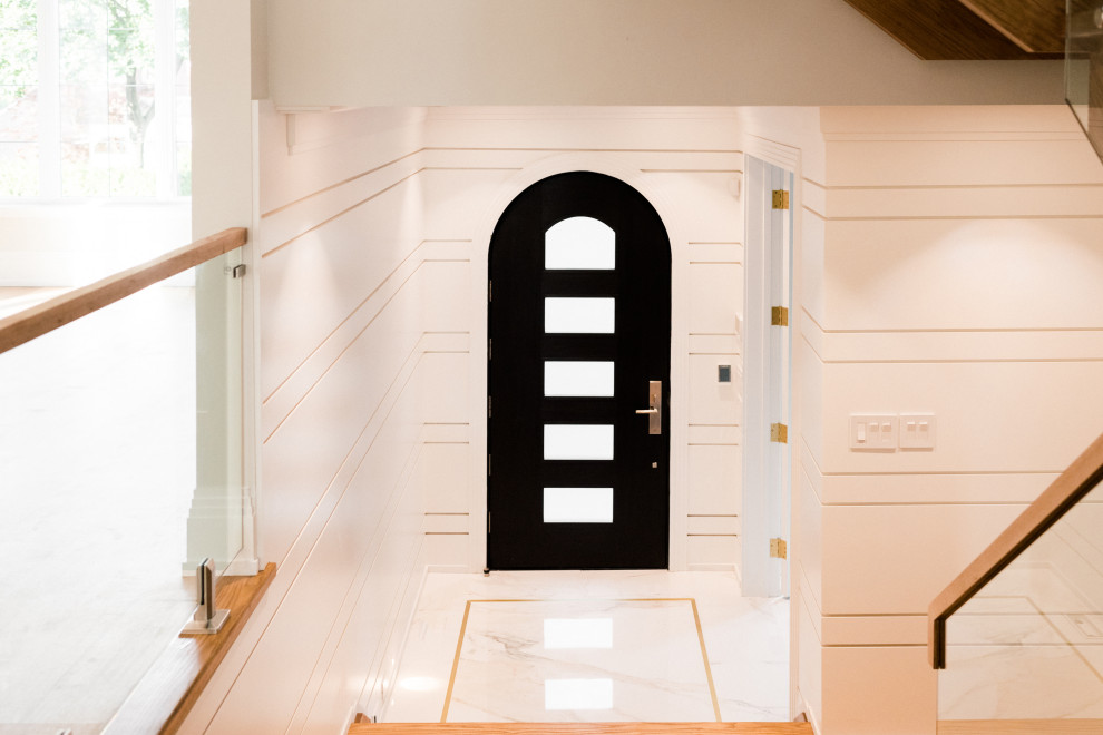 トロントにあるトランジショナルスタイルのおしゃれな玄関 (白い壁、磁器タイルの床、黒いドア、白い床、パネル壁) の写真
