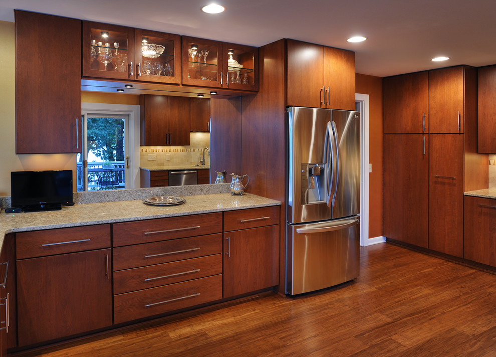 This is an example of a modern eat-in kitchen in Nashville with an undermount sink, medium wood cabinets, granite benchtops, stainless steel appliances, medium hardwood floors and a peninsula.