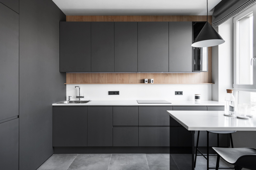 Design ideas for a mid-sized contemporary l-shaped eat-in kitchen in Moscow with an undermount sink, flat-panel cabinets, grey cabinets, solid surface benchtops, white splashback, black appliances, porcelain floors, with island, grey floor and white benchtop.
