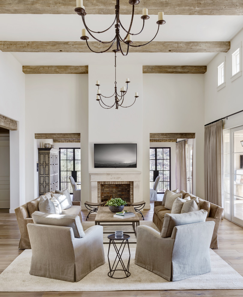 Inspiration for a transitional open concept living room in Phoenix with white walls, medium hardwood floors, a standard fireplace, a brick fireplace surround, a wall-mounted tv, brown floor and exposed beam.