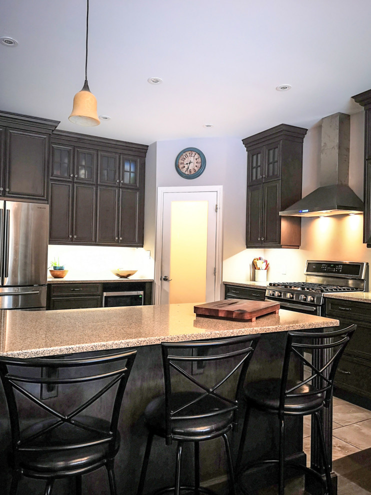 Example of a mid-sized mountain style l-shaped medium tone wood floor and brown floor eat-in kitchen design with a double-bowl sink, recessed-panel cabinets, dark wood cabinets, granite countertops, stainless steel appliances, an island and gray countertops