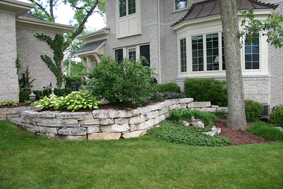 Inspiration for a traditional backyard partial sun garden for summer in Chicago with a retaining wall and natural stone pavers.