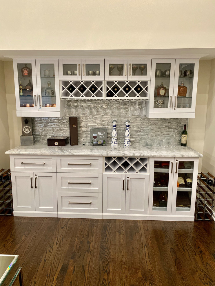 This is an example of a mid-sized traditional single-wall home bar in Detroit with shaker cabinets, white cabinets, granite benchtops, grey splashback, matchstick tile splashback, dark hardwood floors, brown floor and multi-coloured benchtop.