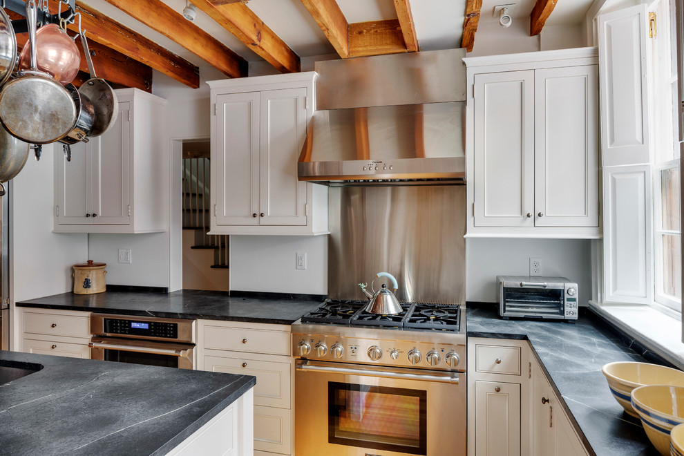 Photo of a country l-shaped separate kitchen in Boston with an undermount sink, recessed-panel cabinets, white cabinets, soapstone benchtops, stainless steel appliances, light hardwood floors and with island.