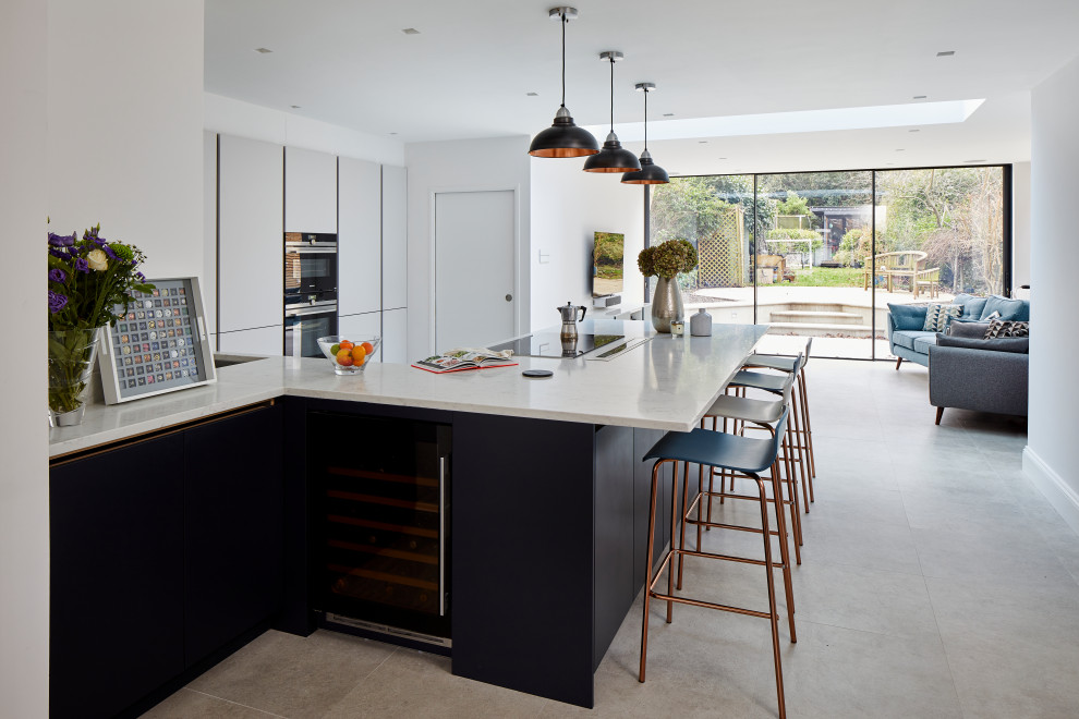 Large modern l-shaped open plan kitchen in London with a single-bowl sink, flat-panel cabinets, white cabinets, marble benchtops, white appliances, a peninsula, white benchtop and coffered.