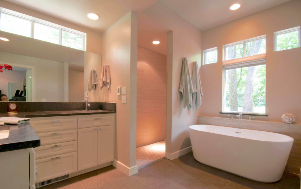 Idéer för att renovera ett stort funkis svart svart en-suite badrum, med ett fristående badkar, en kantlös dusch, beige kakel, travertinkakel, granitbänkskiva, med dusch som är öppen, svart golv, kalkstensgolv, skåp i shakerstil och vita skåp
