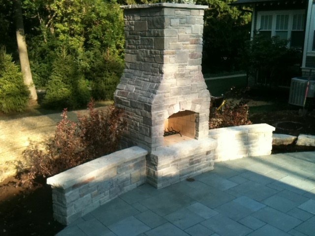 This is an example of a mid-sized traditional backyard patio in Chicago with a fire feature, natural stone pavers and no cover.