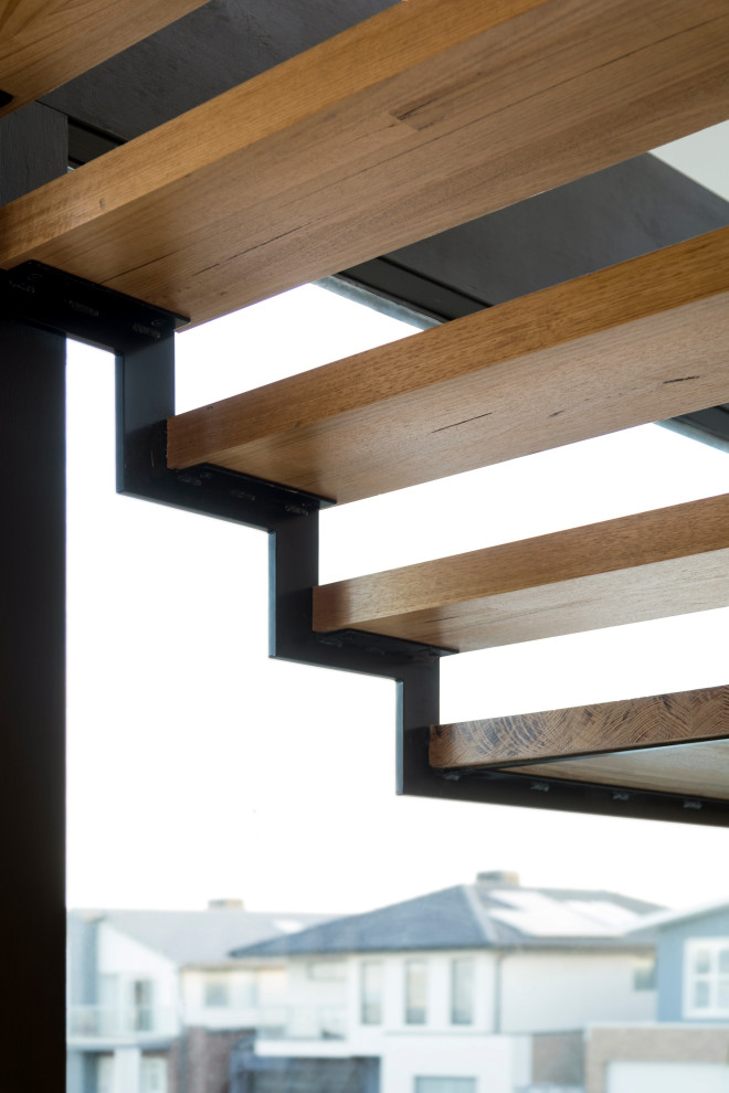 Photo of a mid-sized contemporary wood floating staircase in Melbourne with open risers, metal railing and wood walls.
