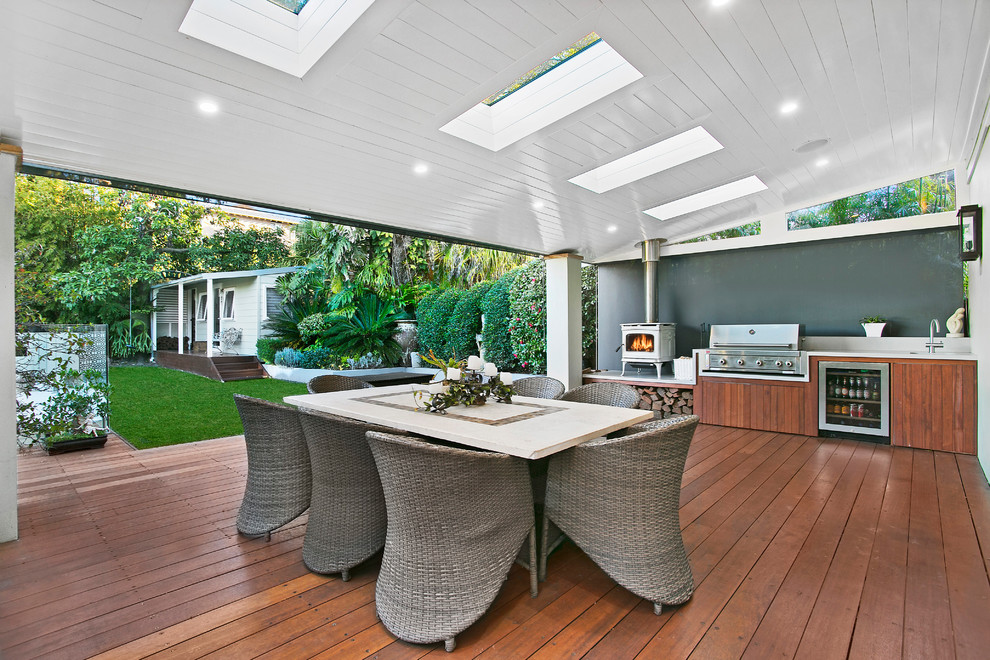 Large transitional backyard verandah in Sydney with an outdoor kitchen, decking and a roof extension.